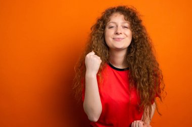 Takım üniforması giyen mutlu, genç, gülümseyen futbol taraftarı kadın en sevdiği futbol takımının zaferiyle seviniyor..