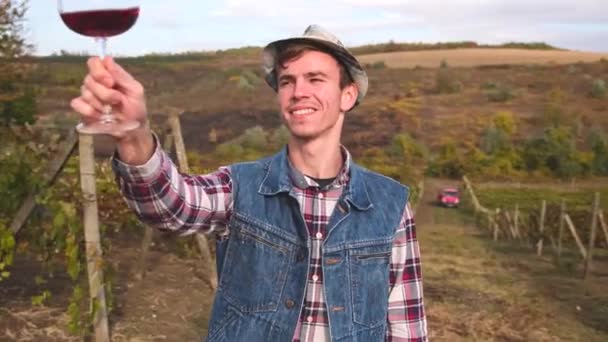 Agriculteur homme avoir heureux expression faciale être à l'extérieur sur son vignoble tenant un verre de vin à son bras longueur regarder. — Video