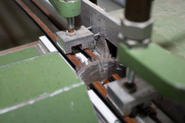 Close up photo of a construction machine for manufacturing of skirting boards in a factory automatically cutting them in pieces.