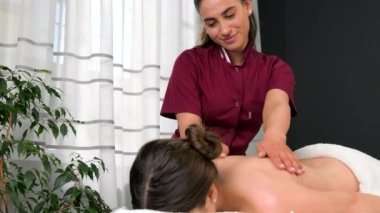 Üniformalı mutlu masör müşterisine sırt masajı yapıyor. Yumuşak ve yumuşak bir cilt için..