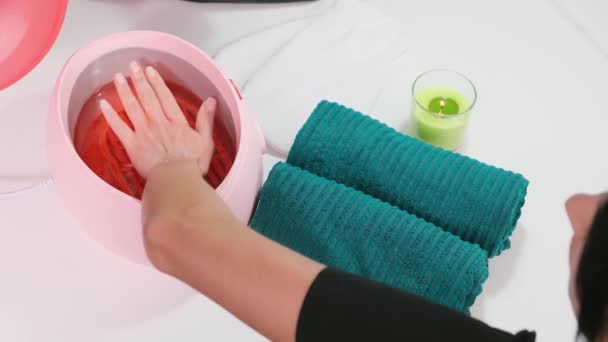 Process paraffin treatment of female hands in beauty salon, woman pulls her hand out of the parrafin bath. — ストック動画