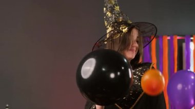 Joyful video of throwing balloons at the girl wearing magician clothes at the Halloween party and feeling happy.