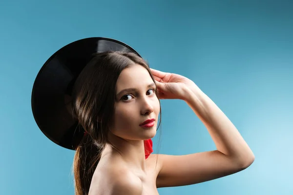 Close up photo of cute sensitive young lady with naked shoulders holding music record black color behind her head. High quality photo