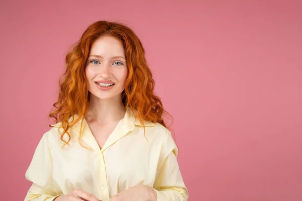 Sarı elbiseli, güzel, güzel, kızıl saçlı bayan kameraya poz veriyor ve pembe arka planda fotokopi odası var. Yüksek kalite fotoğraf