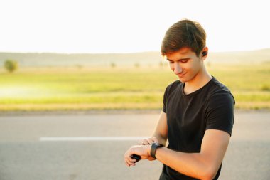 Happy athlete looking the time results at his smart watch on the street. High quality photo