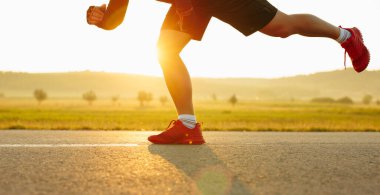 Sprinting man runner sprinter athlete running shoes and legs on track and field lane run race competing fast panoramic banner background. High quality photo