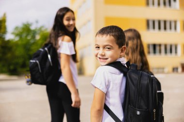 Group of students leaving for school. in the foreground the handsome boy with a black satchel. High quality photo