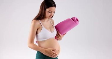 Close-up shot of pregnant belly and womans hand stroking tummy while other hand is holding yoga mat. Healthy lifestyle, sports and pregnancy concept. High quality 4k footage