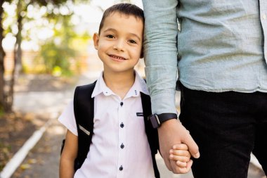 Schoolboy holding hands with his father or smiling at the camera. High quality photo