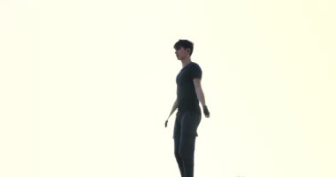 Sports man silhouette doing jumping exercises with skipping rope outside at the pier on sunrise. High quality 4k footage