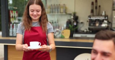 Barista, kafenin önündeki masada oturan güzel müşterilerine kahve servisi yapar. Yüksek kalite 4k görüntü