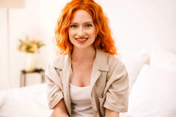 Yatakta Oturmuş Kameraya Gülümseyen Turuncu Saçlı Şirin Bir Kızın Portresi — Stok fotoğraf