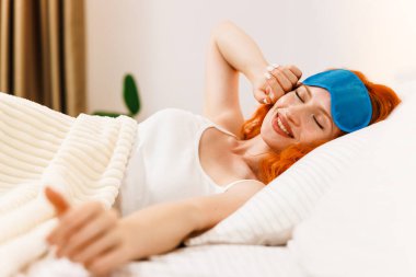 Çekici bir kızın portresi. Battaniyenin altında yattıktan sonra kötü vakit geçirmekten zevk alıyor. Gözlerini kapalı tutarak esnetiyor. İyi günler sağlık konsepti. Yüksek kalite fotoğraf