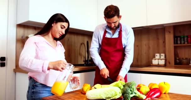 Kadın Kocası Yemek Pişirirken Ona Bir Bardak Taze Portakal Suyu — Stok video
