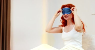 Güzel, genç, gülümseyen bir kadın sabah uyanıyor ve yatağında uzanıyor ve mutlu görünüyor. İçeride. Yüksek kalite 4k görüntü