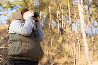 Gezgin, bekâr bir kadın, açık havada giyinmiş, kamerasını tutuyor ve kışın güneşli ve görkemli bir günün fotoğrafını çekiyor. Yüksek kalite fotoğraf