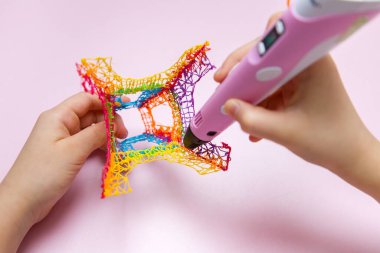 Çocuk 3 boyutlu bir kalem tutuyor ve yeni bir oyuncak yaratıyor..