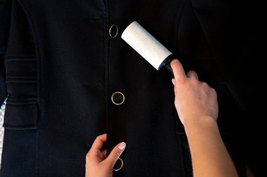 Kadın siyah ceketi pamuklu silindirle temizliyor..