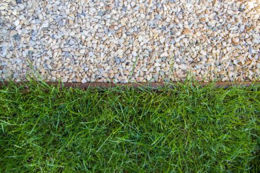 The lawn and pebbles are separated by a border tape.