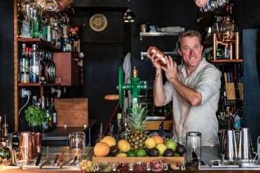 Renkli bir kokteyl barında barmenlik yapan neşeli bir adamın görüntüsü tezgahın arkasında içki sallayan profesyonel bir barmenin görüntüsü, Lizbon, Portekiz.