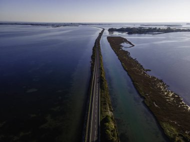 Gorizia, Friuli Venezia Giulia, İtalya yakınlarındaki Grado lagününden geçen güzel bir yolda uçan araçların görüntüsü..