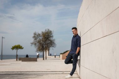 Portekiz, Lizbon 'daki Tejo nehir kenarı boyunca poz veren güzel bir gencin portresi. Şık serbest çalışan mimar şehir merkezindeki şehir konsept binasının yakınında tek başına dinleniyor..