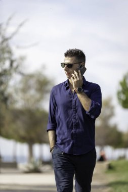 Güzel ve çekici orta yaşlı bir adam Lizbon nehri boyunca tek başına yürüyor ve akıllı telefonu kullanıyor. Resmi kıyafetler giyen klas genç bir girişimci. Başarılı yaşam tarzı kavramı