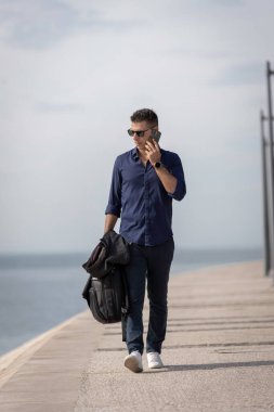 Güzel ve çekici orta yaşlı bir adam Lizbon nehri boyunca tek başına yürüyor ve akıllı telefonu kullanıyor. Resmi kıyafetler giyen klas genç bir girişimci. Başarılı yaşam tarzı kavramı