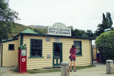 Cardrona, Otago, Yeni Zelanda 'daki Post & Telegraph Tarihi Binası' ndaki eski General Merchant 'ın önünde duran bir turist. 5 Aralık 2010 'da Cardrona, Yeni Zelanda' da çekildi.