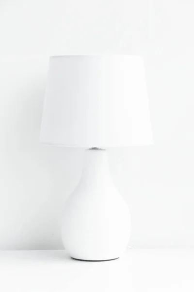 View of white table lamp on the white table in a white room.