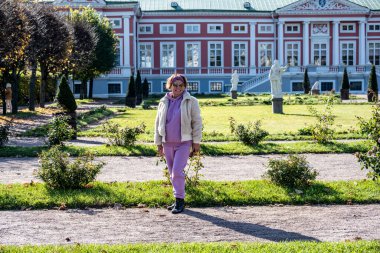 Pembeli kadın, güneşli bir sonbaharda Moskova 'daki eski müze ve park kompleksi Kuskovo' nun arka planına karşı.