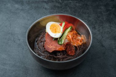 Koyu çimento arkaplanda bir kase soğuk Kore eriştesi.