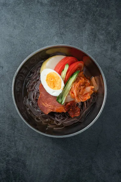 Koyu çimento arkaplanda bir kase soğuk Kore eriştesi.