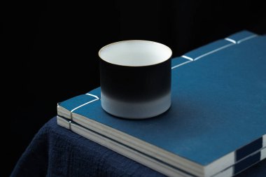 Bir çay fincanı klasik iplik kaplı kitaba konur.