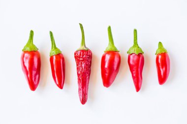 Beyaz arka planda taze biberlerin arasında kuru biber. Seçkin Yarışmacılar.