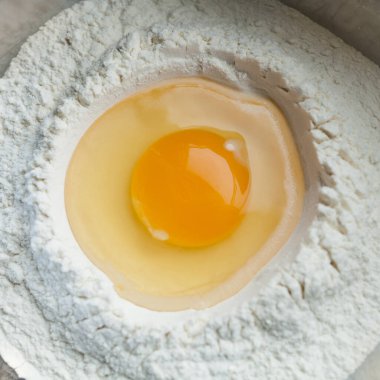 Kırık yumurta ve buğday unu. Ev yapımı makarna, ekmek, hamur işi yapmak için. Üst görünüm.
