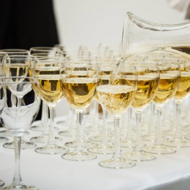 Şarap bardağına dökülen beyaz şarap. Sığ alan derinliği.