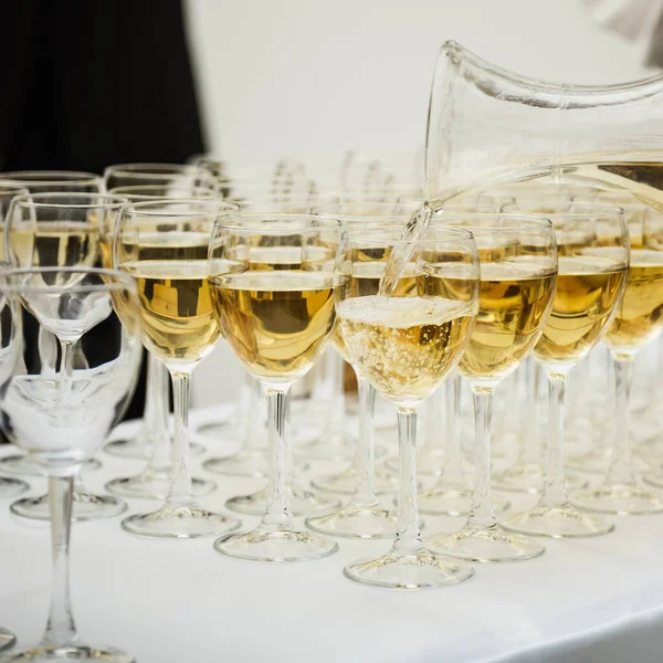 Şarap bardağına dökülen beyaz şarap. Sığ alan derinliği.