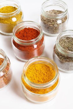 Cam kavanozlar, zerdeçal, kekik, kekik, paprika, köri, pilav. Beyazda izole edilmiş.