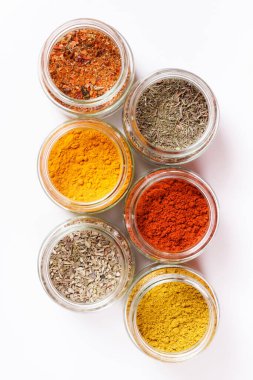 Cam kavanozlar, zerdeçal, kekik, kekik, paprika, köri, pilav. Beyazda izole edilmiş.