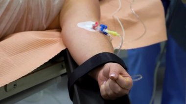 Bir kadının elinde damar yolu. Damarında iğne olan plastik tüp. Ameliyat masası. Hastanedeyiz. Ameliyattan önce hastanın hazırlanması. Tıbbi ekipman