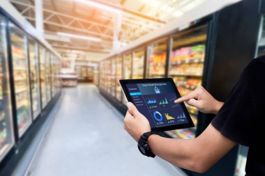 Akıllı perakende yönetim sistemi. Arka plan olarak bulanık süpermarketin tabletini tutan işçi elleri