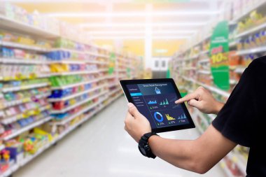 Akıllı perakende yönetim sistemi. Arka plan olarak bulanık süpermarketin tabletini tutan işçi elleri
