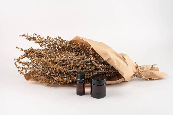 Dried Wormwood herb, Artemisia absinthiu, and glass bottles on white background.