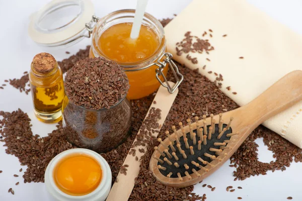 Brown flax seeds, linseeds oil, egg, honey and hair brush on white background. Hair care mask. — Stock Photo, Image