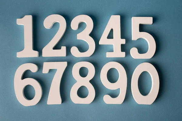 Set of white wooden numbers on blue background. — Stockfoto