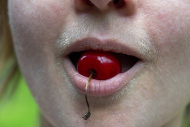Composition of a sweet cherry and a natural hairy upper lip of a body positive young woman. Close up.