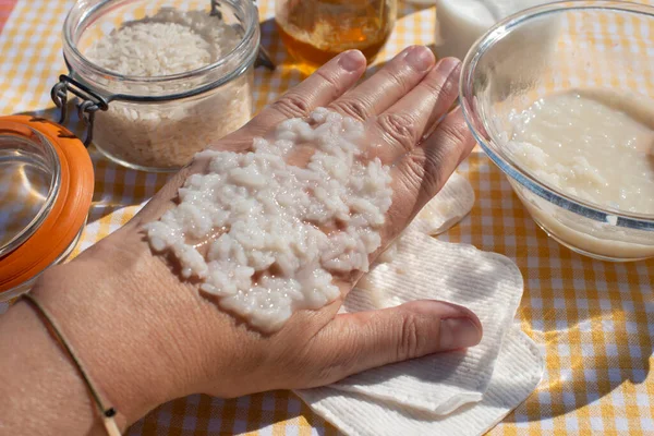 Rice grains on hand. Woman testing rice mask, natural homemade beauty product. Close up.