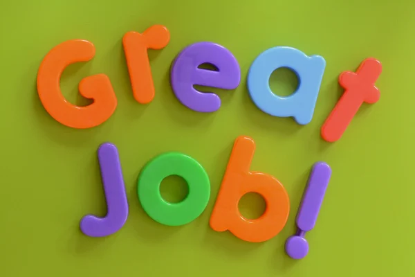 Close up of Great Job! words in colorful plastic letters on green background — Stock Photo, Image