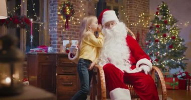 Küçük beyaz kız Noel Baba 'nın yanında duruyor ve ona zevkle bir şeyler anlatıyor. Arka planda kürk ağacı ve yeni yıl süslemeleri